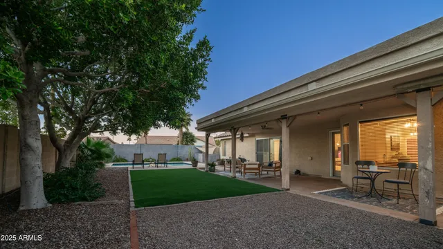 a view of a backyard with table and chairs and a large tree