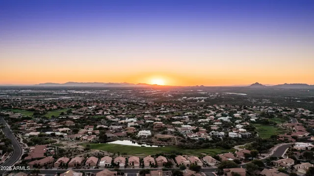 an aerial view of a town with swimming pool and mountains