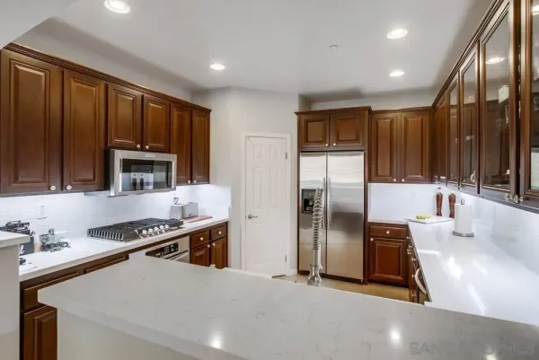 a kitchen with stainless steel appliances granite countertop a refrigerator a stove and a sink