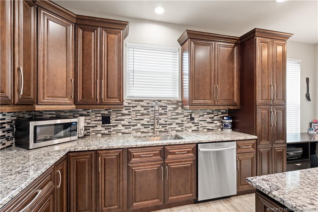 1268 Southeast Kirk Street Stuart, FL 34997 - Photo 26 of 63 a kitchen with stainless steel appliances granite countertop a sink stove and cabinets