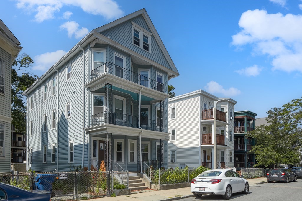 a front view of a building with lot of cars and trees