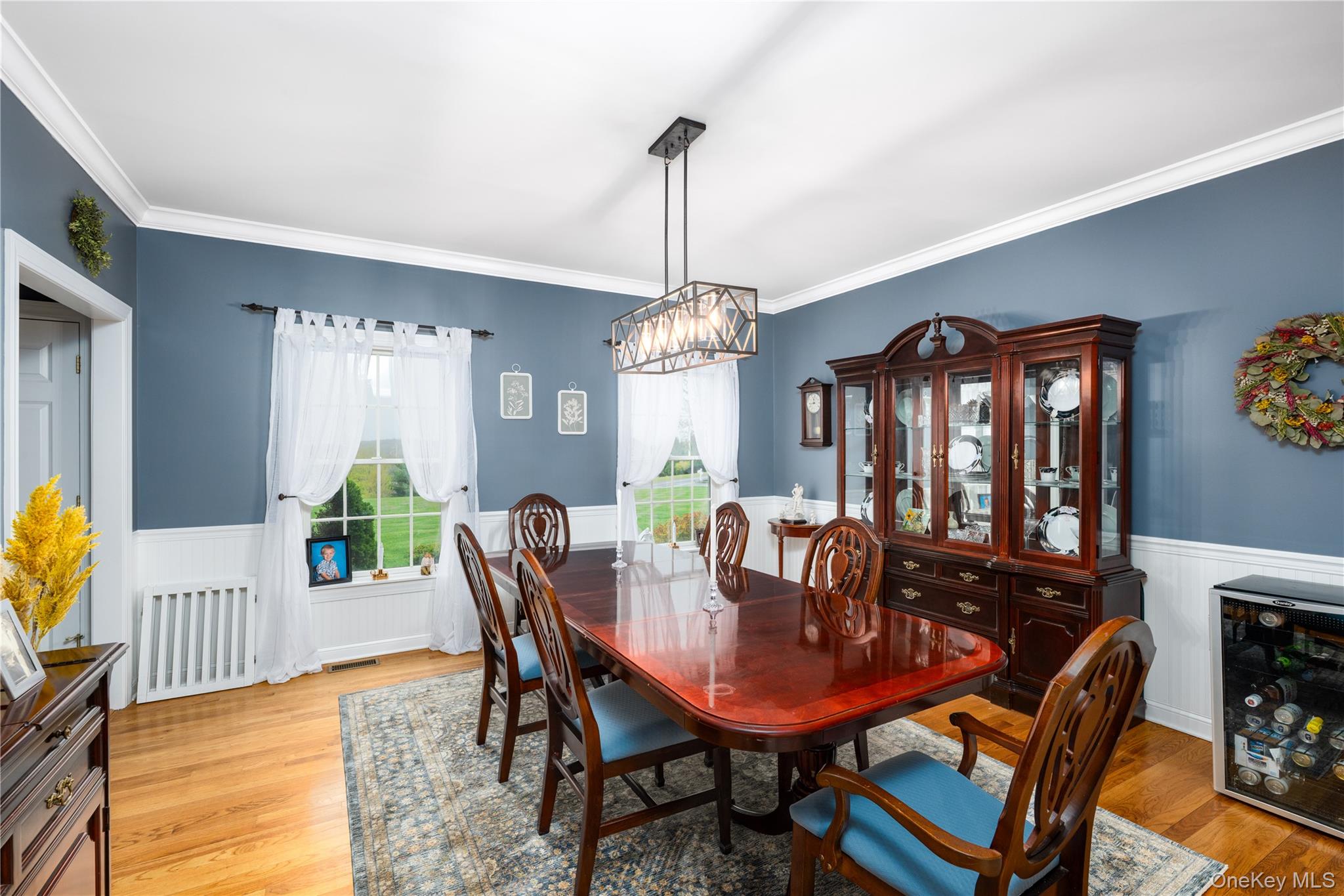 60 Idlewild Road Marlboro, NY 12542 - Photo 11 of 37 Hardwood flooring complements the wainscoting and crown molding in this room, featuring a geometric chandelier