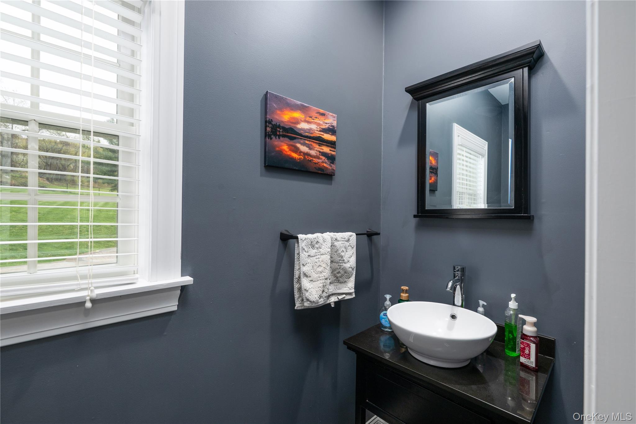 60 Idlewild Road Marlboro, NY 12542 - Photo 17 of 37 First floor Powder room featuring a single window with blinds, a wall-mounted mirror with a black frame, a dark wood-finish vanity with a vessel sink, and a chrome faucet