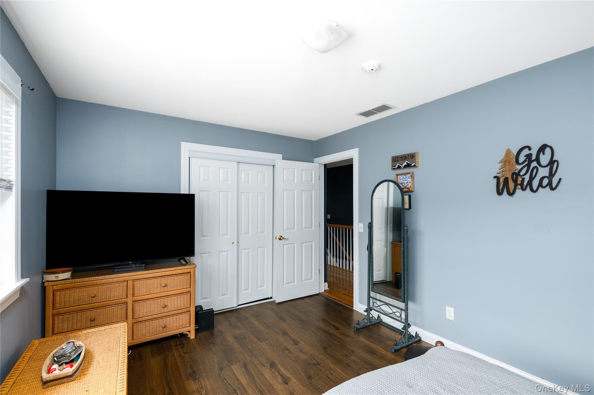 60 Idlewild Road Marlboro, NY 12542 - Photo 27 of 37 Bedroom featuring wood-finish flooring, light blue walls, a white trim window, and white bi-fold closet doors