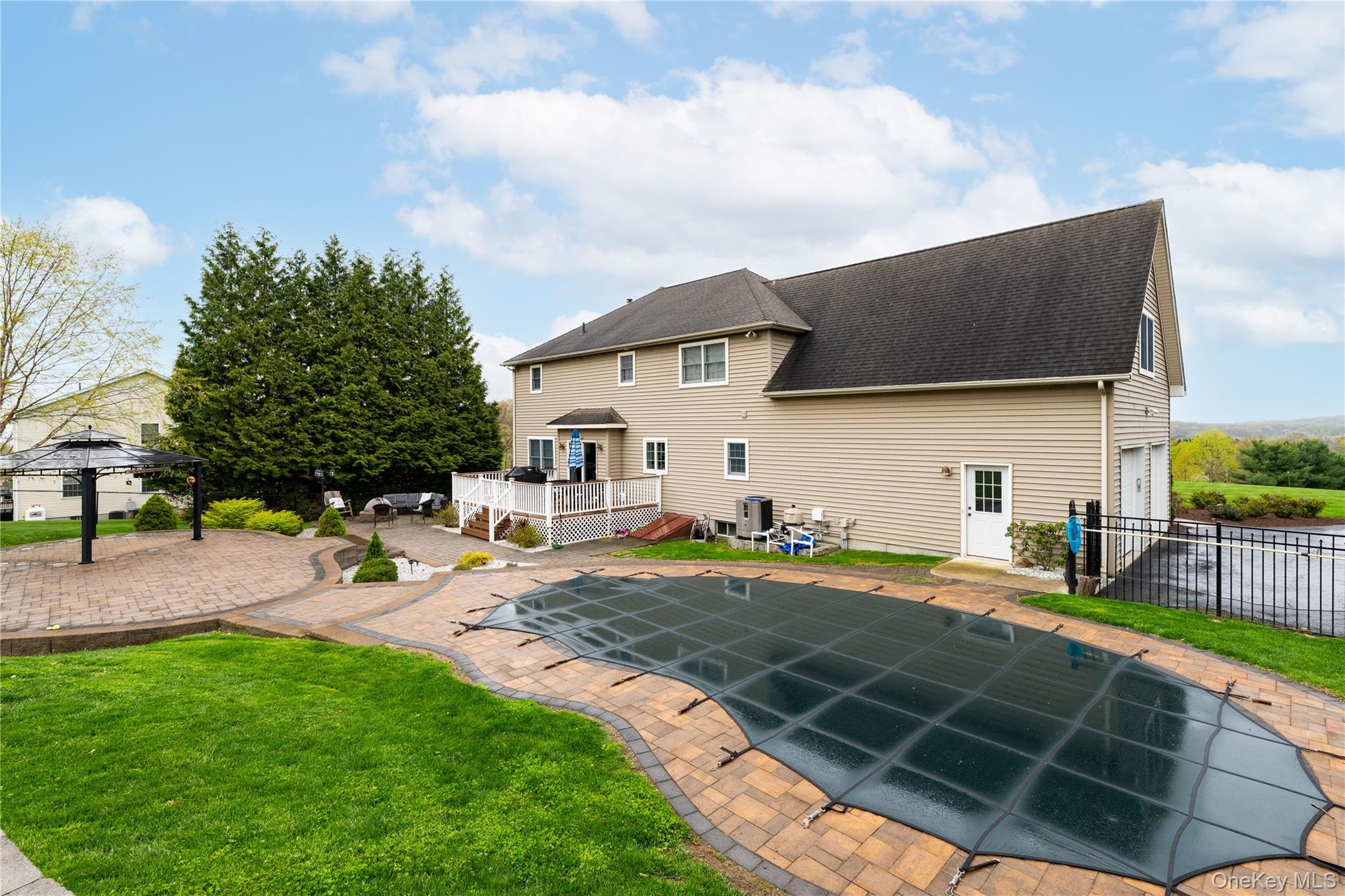 60 Idlewild Road Marlboro, NY 12542 - Photo 3 of 37 Expansive backyard featuring a covered pool with paver surround, multiple paver patio areas, a raised Trex deck, and a built-in two-car garage
