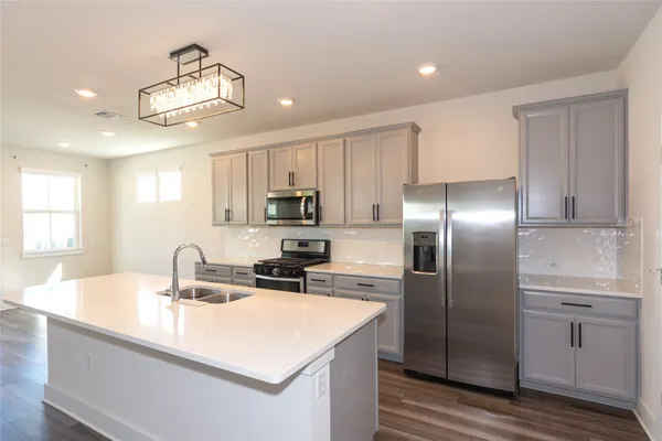 a kitchen with stainless steel appliances a sink a refrigerator and cabinets