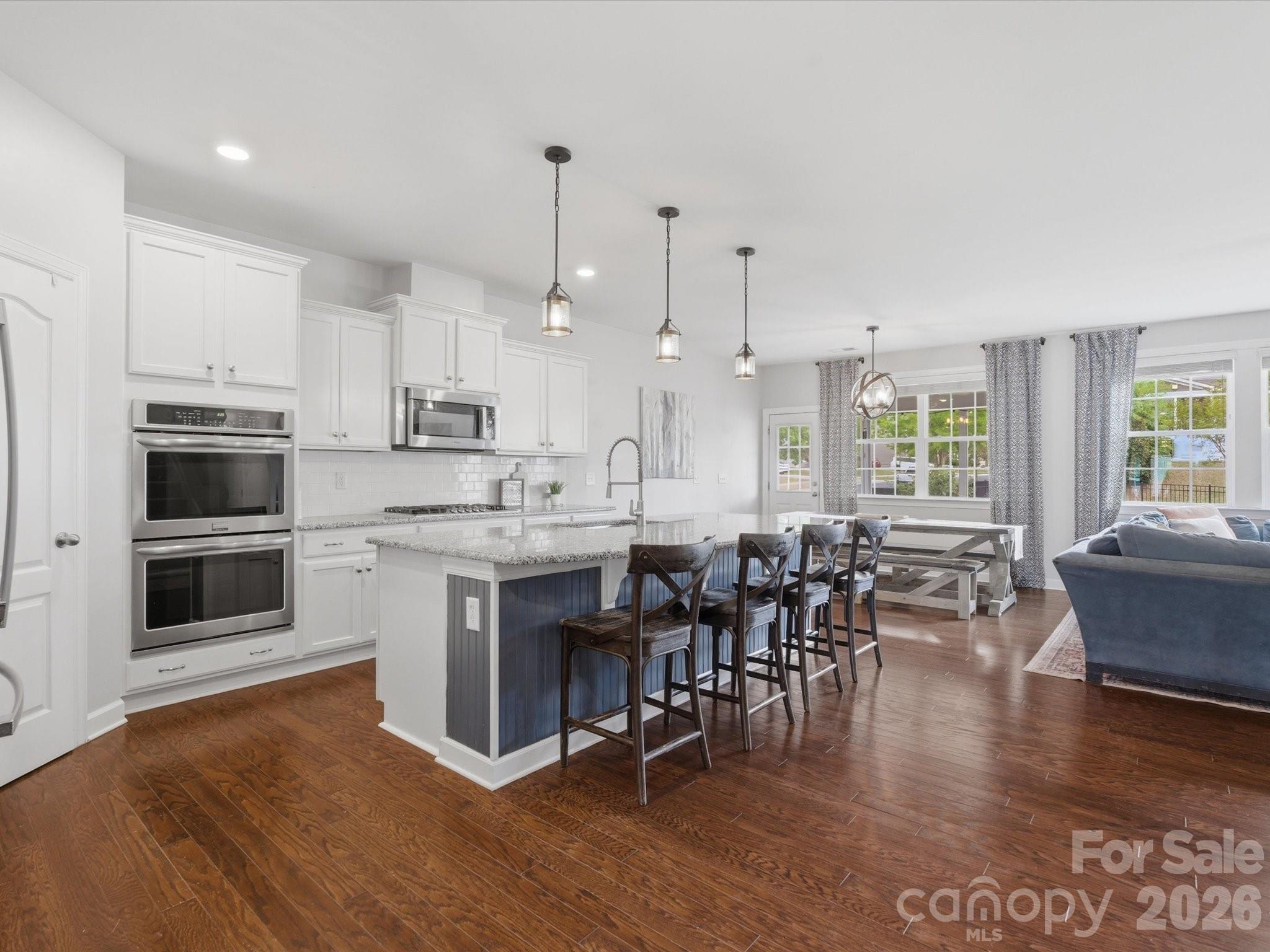 932 Twin Valley Way Fort Mill, SC 29715 - Photo 7 of 48 a kitchen with stainless steel appliances granite countertop a stove top oven a sink a dining table and chairs with wooden floor