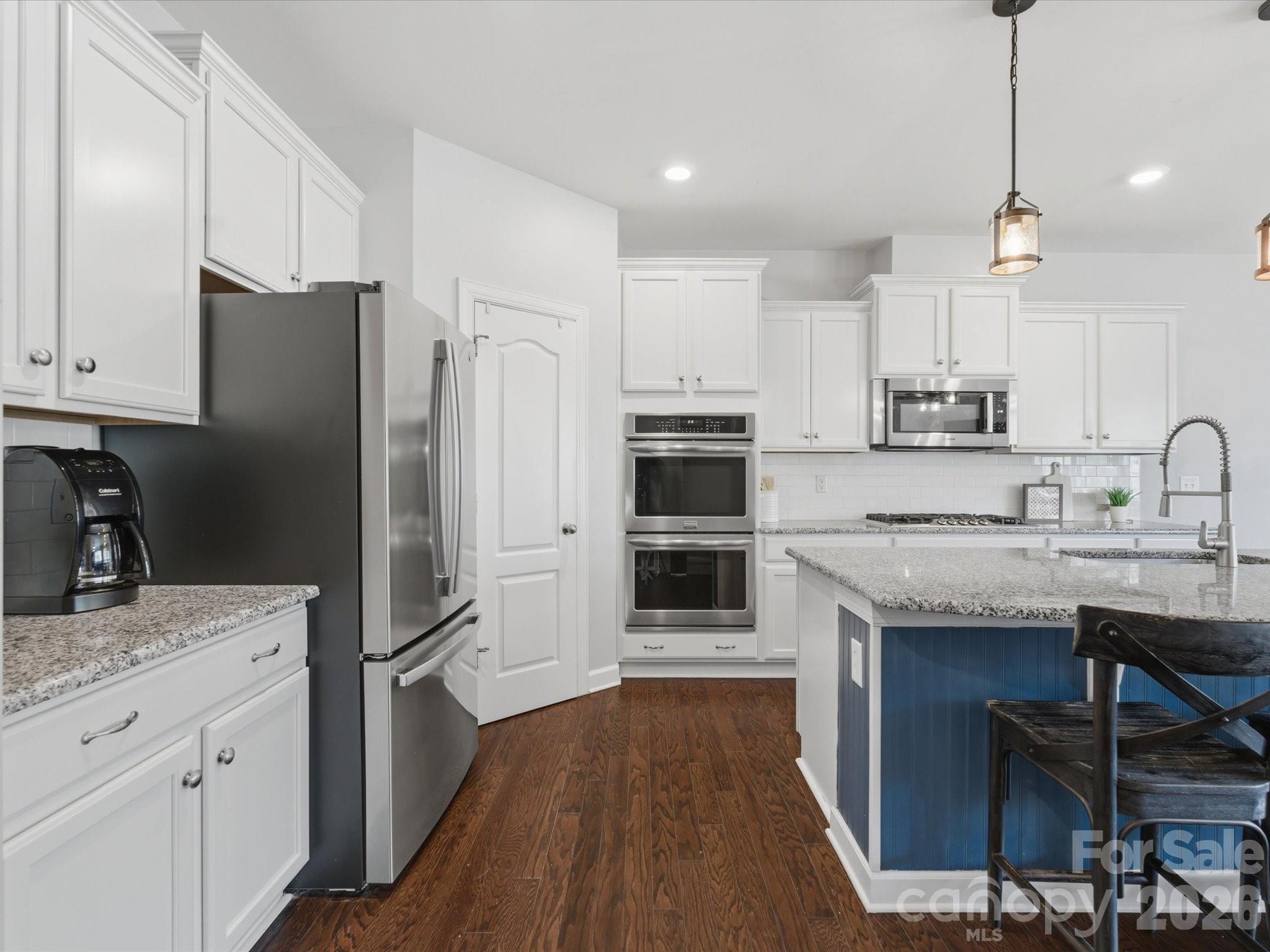 932 Twin Valley Way Fort Mill, SC 29715 - Photo 10 of 48 a kitchen with stainless steel appliances granite countertop a refrigerator a sink dishwasher a stove and white countertops with wooden floor