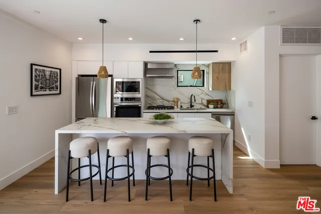 a kitchen with stainless steel appliances kitchen island a refrigerator and microwave