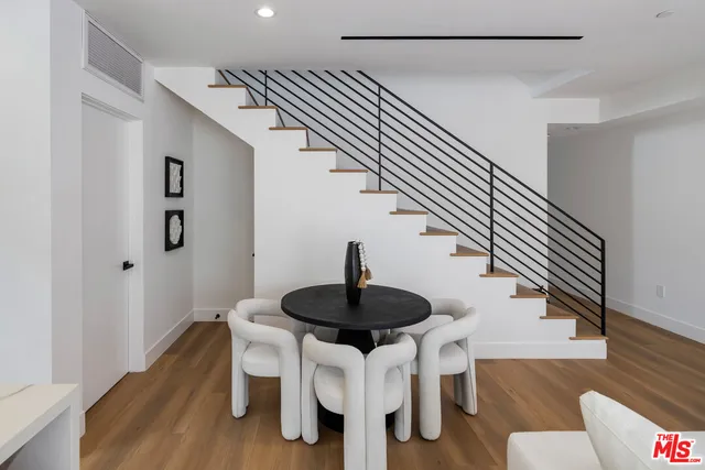 a dining room with wooden floor a chandelier a wooden table and chairs
