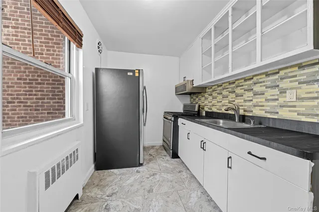 a kitchen with granite countertop white cabinets and refrigerator
