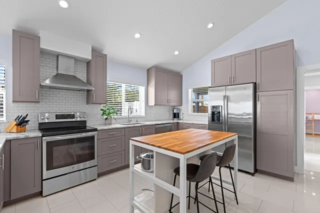a kitchen with stainless steel appliances granite countertop a table chairs stove top oven and refrigerator