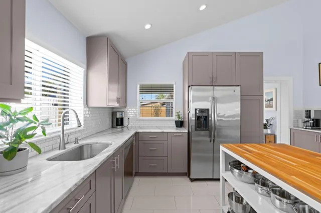 a kitchen with stainless steel appliances granite countertop a sink a stove a refrigerator a washer dryer and cabinets