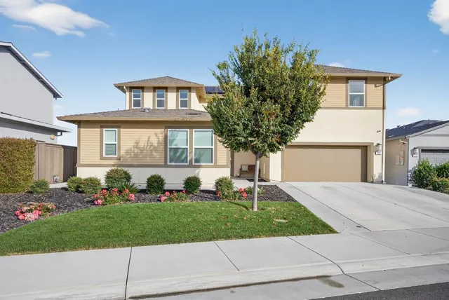 a front view of a house with a yard and potted plants