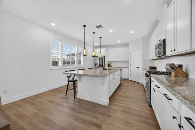 a kitchen with kitchen island granite countertop a sink a counter space stainless steel appliances and cabinets