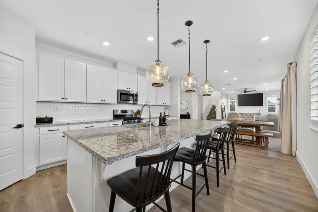 a kitchen with stainless steel appliances granite countertop a sink a stove and a wooden floors