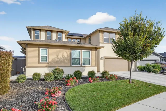 a front view of a house with a yard and potted plants