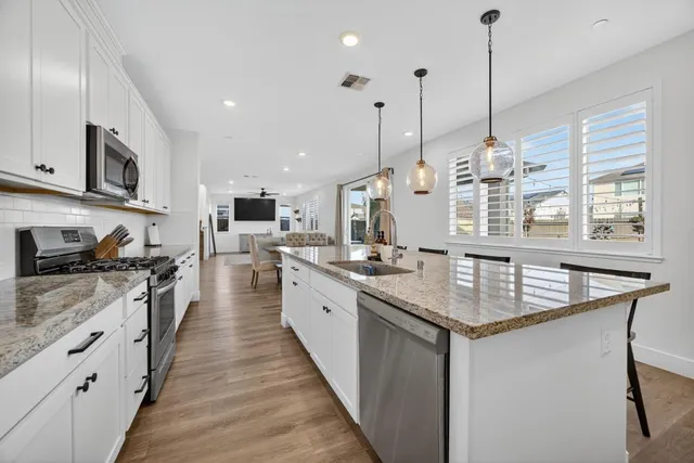 a kitchen with stainless steel appliances granite countertop a white cabinets a stove top oven a chimney and a kitchen view