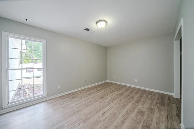 an empty room with wooden floor and windows