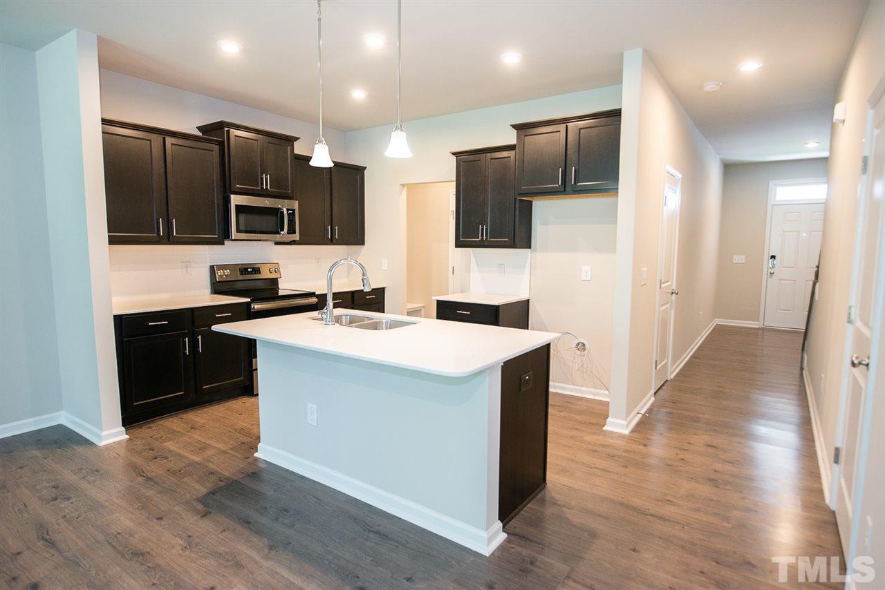 3645 Water Mist Lane, Unit 9 Raleigh, NC 27604 - Photo 3 of 26 a kitchen with kitchen island stainless steel appliances a sink cabinets and a wooden floor