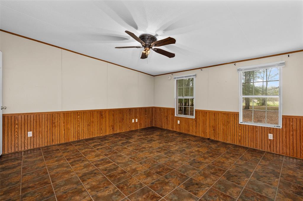 334 Destiny Lane Keatchie, LA 71046 - Photo 12 of 29 Empty room with wood walls, wainscoting, a ceiling fan, and ornamental molding