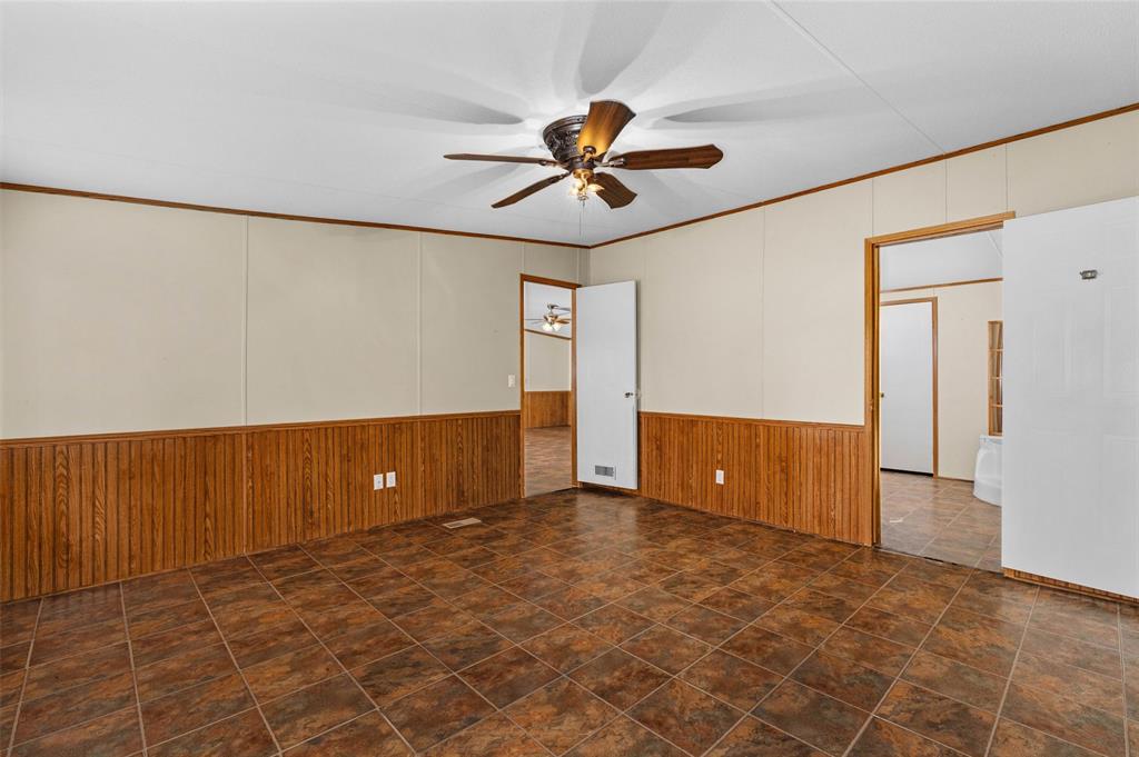 334 Destiny Lane Keatchie, LA 71046 - Photo 13 of 29 Unfurnished room featuring ornamental molding, wood walls, wainscoting, and ceiling fan