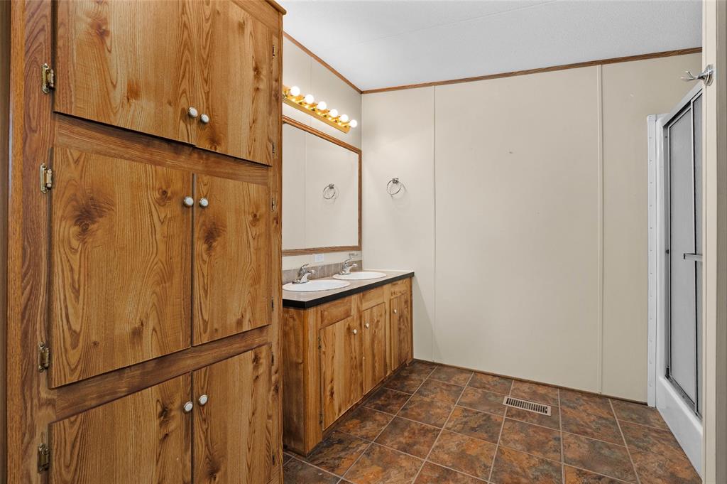 334 Destiny Lane Keatchie, LA 71046 - Photo 14 of 29 Bathroom with double vanity, stone finish floors, a stall shower, and ornamental molding