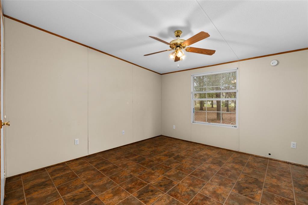 334 Destiny Lane Keatchie, LA 71046 - Photo 16 of 29 Spare room with ornamental molding, a ceiling fan, and stone finish floors