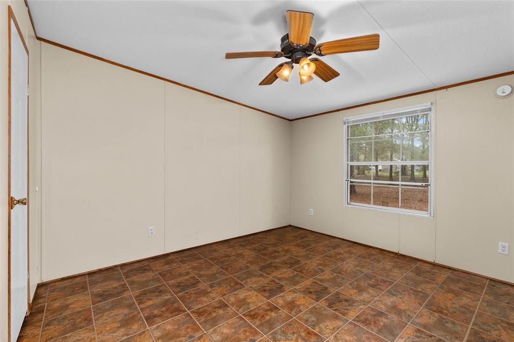 334 Destiny Lane Keatchie, LA 71046 - Photo 17 of 29 Empty room with crown molding, a ceiling fan, and stone finish floors