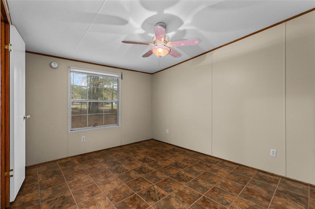 334 Destiny Lane Keatchie, LA 71046 - Photo 20 of 29 Empty room featuring a ceiling fan, crown molding, and stone finish floors