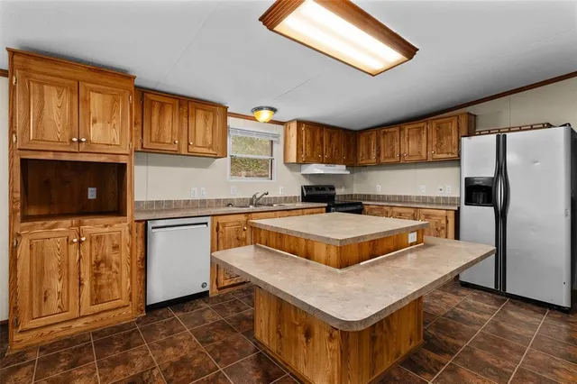 a kitchen with granite countertop a stove a sink dishwasher and a refrigerator