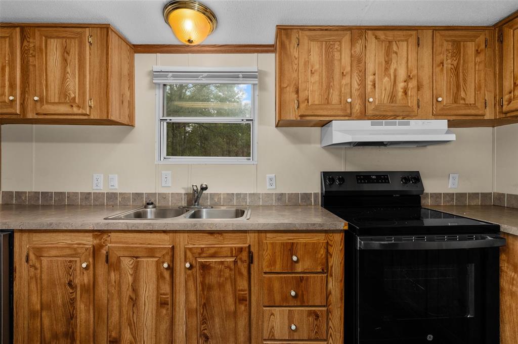 334 Destiny Lane Keatchie, LA 71046 - Photo 9 of 29 Kitchen with black / electric stove, brown cabinets, and under cabinet range hood