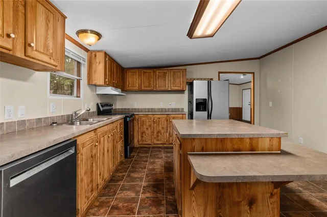 a kitchen with kitchen island granite countertop a stove and a sink