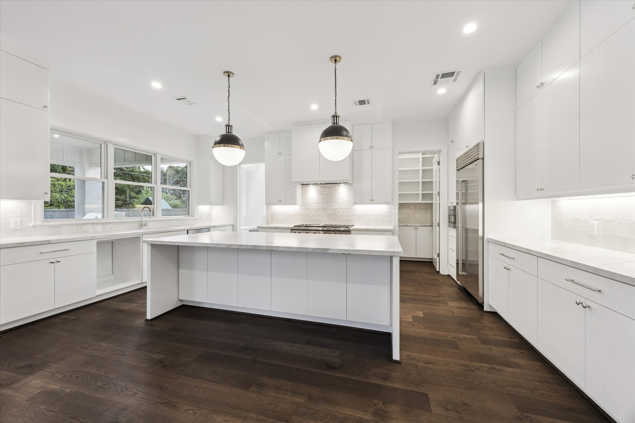 3011 Deal Street Houston, TX 77025 - Photo 16 of 45 a large kitchen with white cabinets and wooden floor