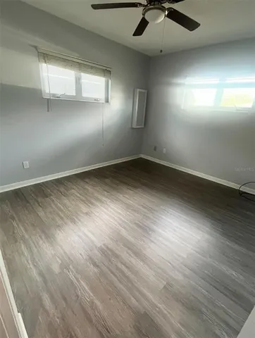 an empty room with windows and fan