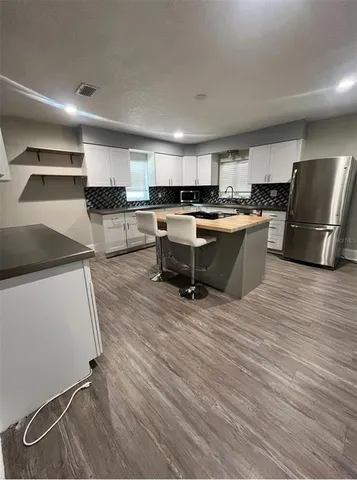a kitchen with a sink dishwasher a refrigerator and cabinets with wooden floor