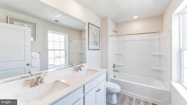 a bathroom with a bathtub shower sink mirror vanity and a toilet