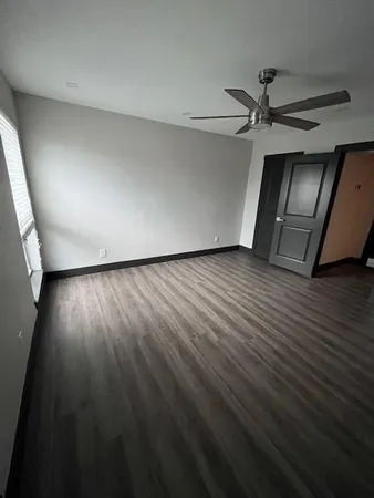 an empty room with wooden floor closet and windows