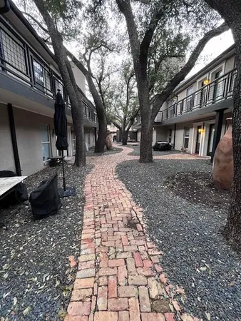 a pathway of a house with backyard and trees