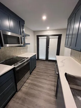 a large kitchen with stainless steel appliances wooden floor and a refrigerator