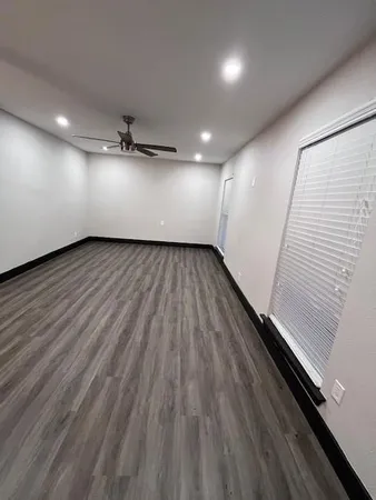 an empty room with wooden floor and windows