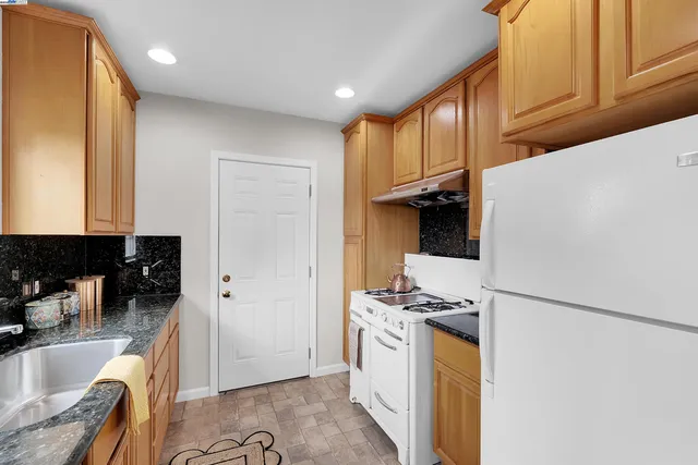 a kitchen with stainless steel appliances granite countertop a refrigerator and a stove top oven