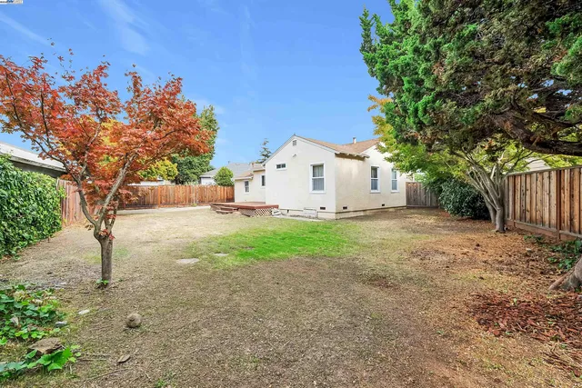 a view of a white house next to a road and yard