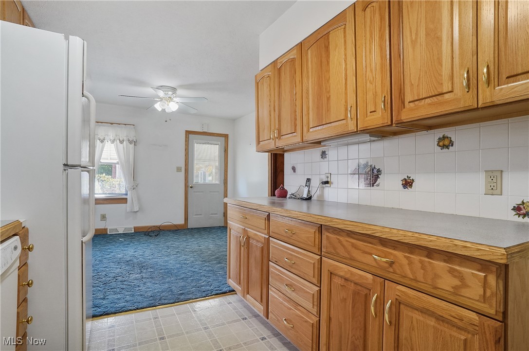 2809 McElwain Road Akron, OH 44312 - Photo 23 of 38 Kitchen featuring white appliances, decorative backsplash, light countertops, a ceiling fan, and light carpet in dining room