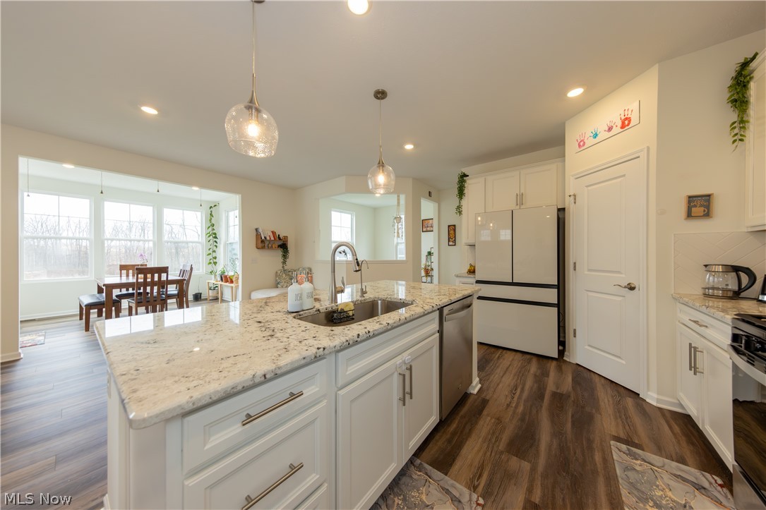 766 River Run Road Aurora, OH 44202 - Photo 17 of 49 Kitchen with stainless steel appliances, a kitchen breakfast bar, white cabinetry, a center island with sink, and light granite countertops