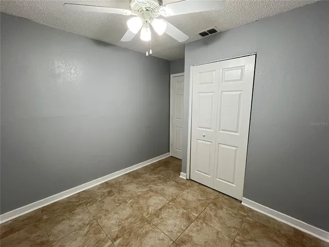 an empty room with a ceiling fan and closet