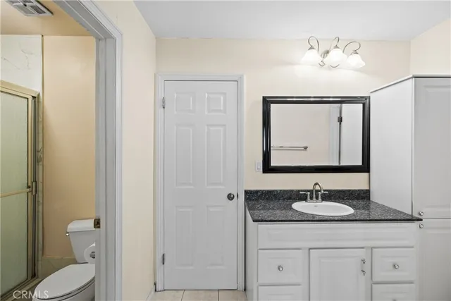 a bathroom with a granite countertop sink toilet and mirror