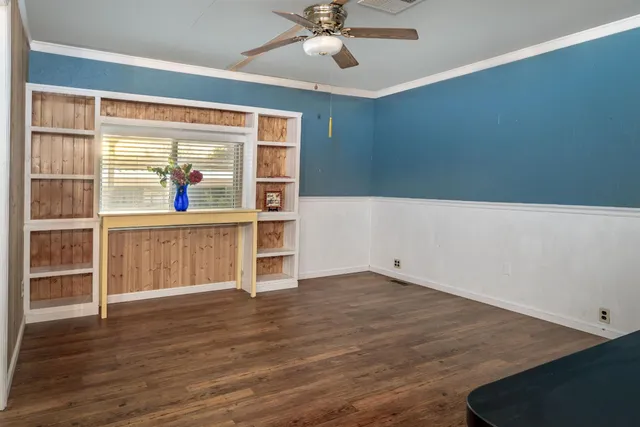 a view of an empty room with a window and wooden floor