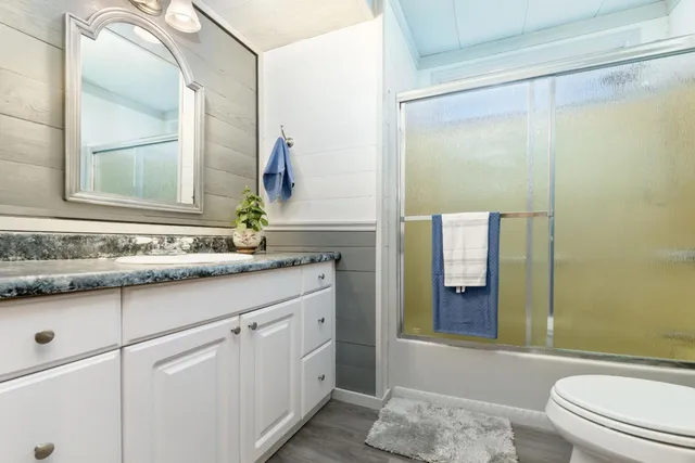 a bathroom with a granite countertop sink a toilet and shower