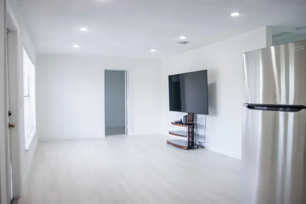 an empty room with a chandelier fan and windows